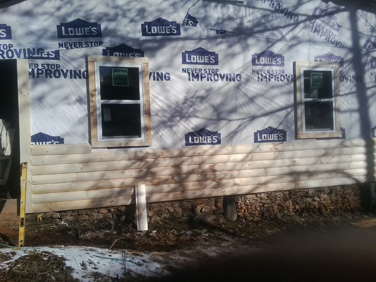 House wrap and new log siding going up on an exterior wall in New Bedford