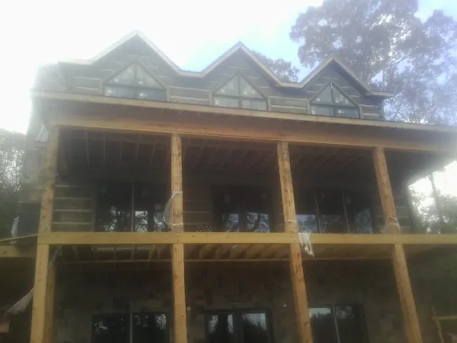 Dormers and porch framing on a large log home under construction — Roof Coating work by our crew in New Bedford