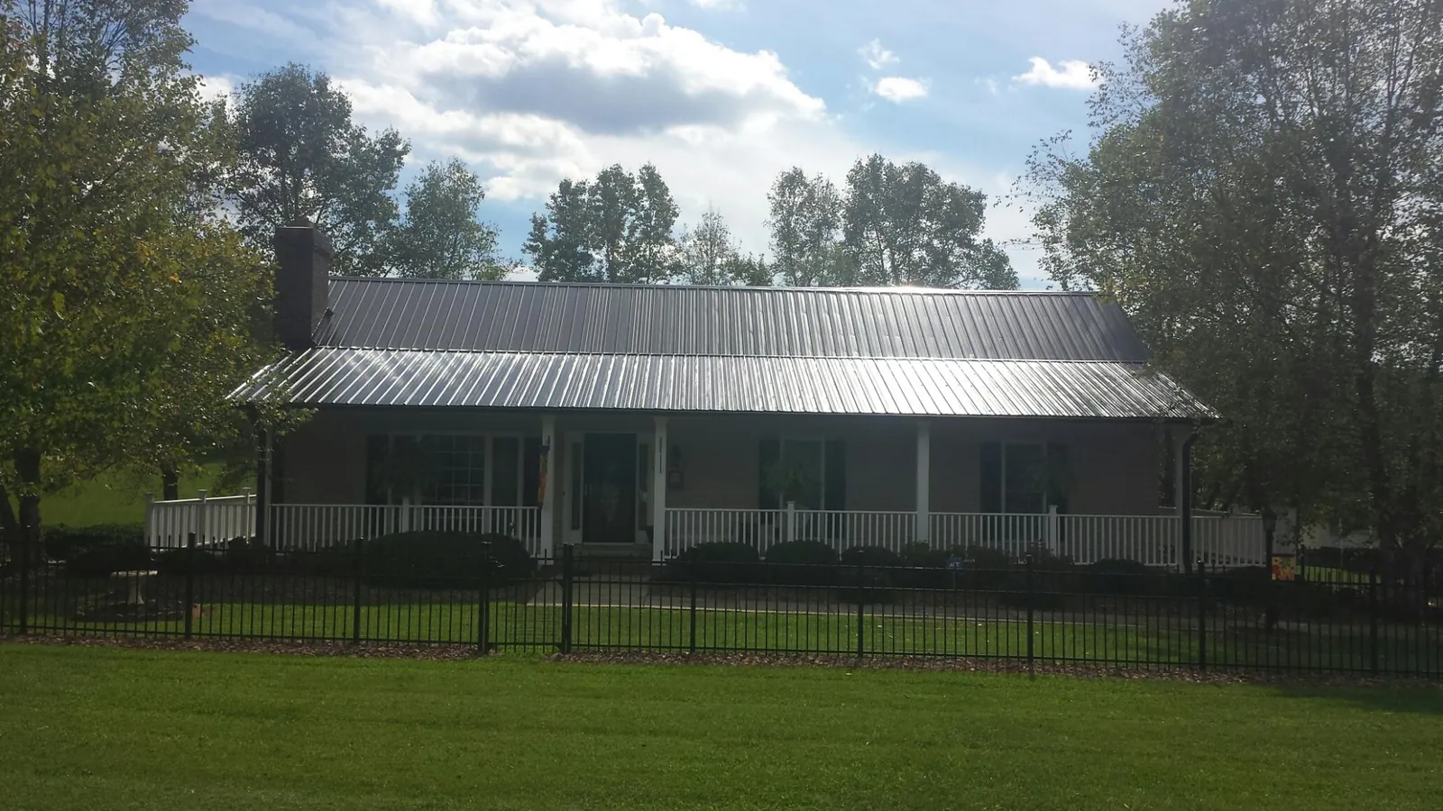 Gray metal roof on a brick ranch with a full width front porch — Gutter Guard Installation work by our crew in New Bedford